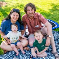 Sawyer Johnson '18 sitting on picnic blanket with wife and two kids